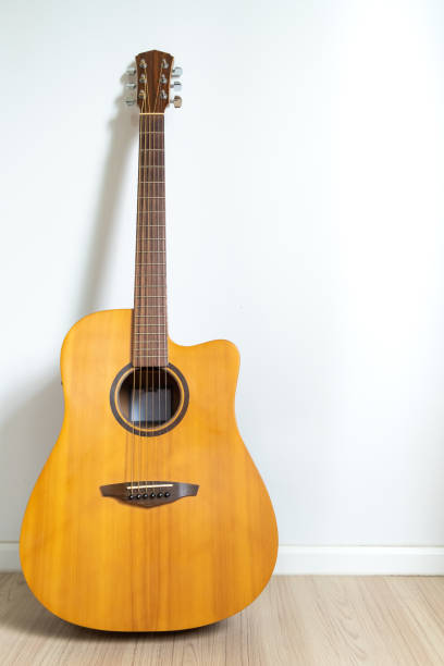istock An acoustic dreadnought guitar leaned against the white wall background. Veritcal image copy space. 1395094113