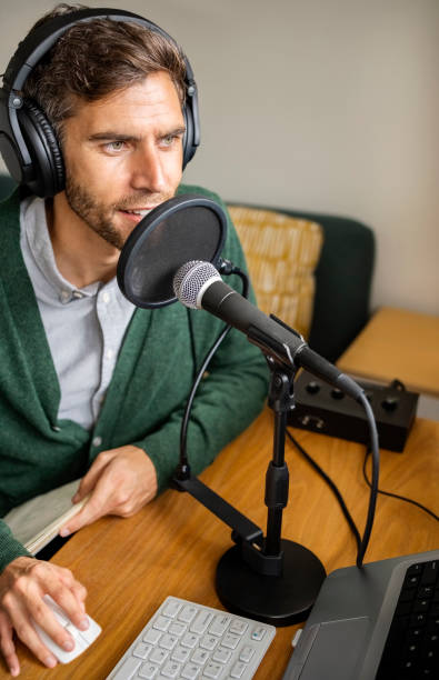 istock Man using laptop and recording podcast at home studio 1395095135