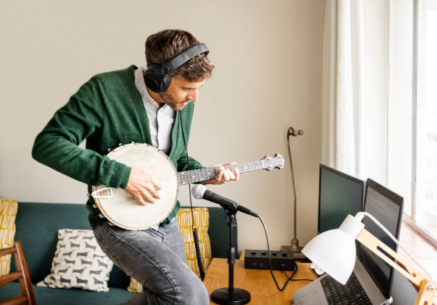 istock Man playing a banjo in his home recording studio 1395095285