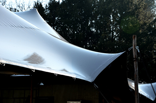 white tarpaulin taut, shading from the sun and rain over the terrace of the restaurant, on the playground in the kindergarten, on the platform. just a mast and taut ropes attached firmly to the ends, tarp