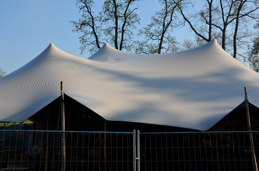 white tarpaulin taut, shading from the sun and rain over the terrace of the restaurant, on the playground in the kindergarten, on the platform. just a mast and taut ropes attached firmly to the ends, tarp