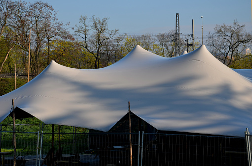 white tarpaulin taut, shading from the sun and rain over the terrace of the restaurant, on the playground in the kindergarten, on the platform. just a mast and taut ropes attached firmly to the ends, tarp