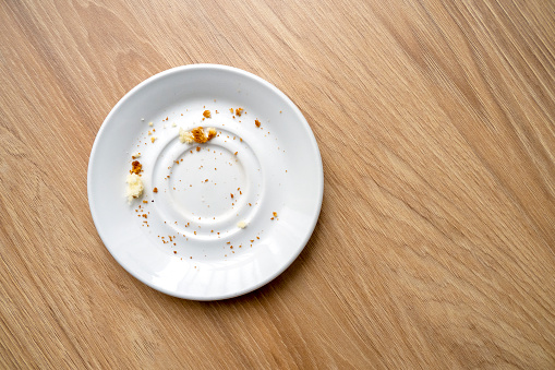 White ceramic dessert plate with pastry leftover, crumbs, top view