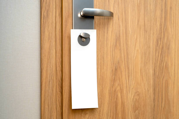 호텔의 문 손잡이에 모형으로 종이 빈 라벨이 붙어 있습니다. 나무 소나무 문과 텍스트를위한 공간이있는 흰색 긴 시트. - hanger 뉴스 사진 이미지