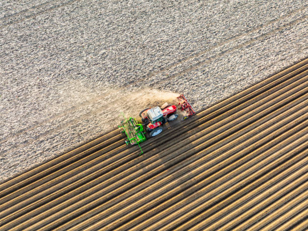 трактор в весеннее время проращивает картофельные просачивания в почву - высаживать средство передвижения стоковые фото и изображения