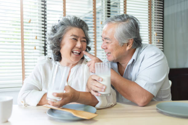 chiński dziadek i babcia bawią się i trzymają szklanki mleka razem - 60s senior adult breakfast cheerful zdjęcia i obrazy z banku zdjęć