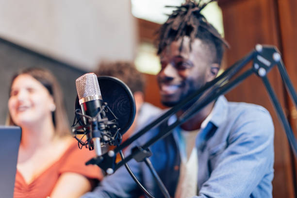 istock detail on microphone in foreground with blurred people in background during live streaming vlogging podcast 1395102639