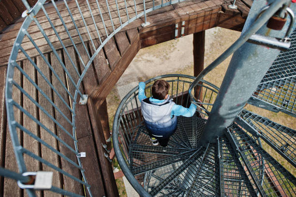 istock Boy walk at spiral staircase on wooden observation tower. 1395102820