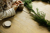 木製のクラフトテーブルで杉の花輪を作る女の子。サイザルの糸を切る子供。