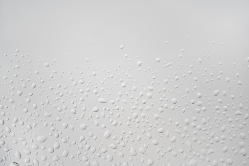 perfect backlit chaotic water drops on white light glass background. Natural hydration