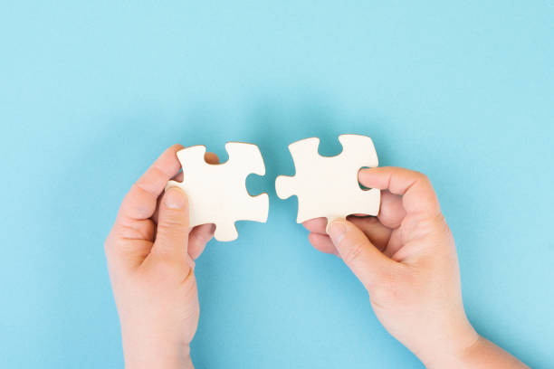 istock Holding two pieces of a puzzle in the hands, connecting together as a team, solving a problem, strategy and communication concept 1395105603