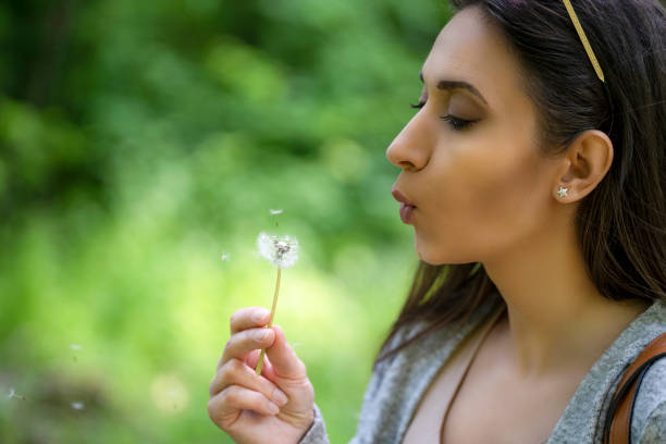 istock Attractive woman blows in a dandelion flower 1395107551