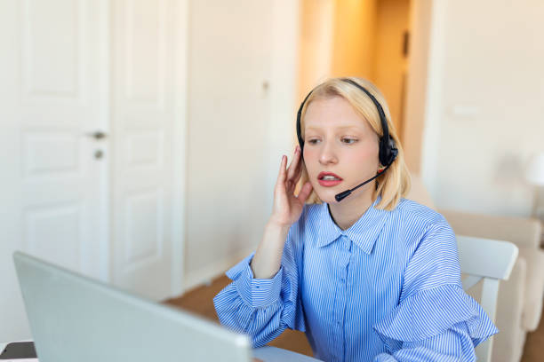istock Smiling young woman using laptop at home, looking at screen, chatting, wearing wireless headset having video conference . business trainer tutoring by webcam, online training, e-coaching concept 1395108237
