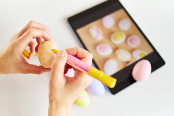 istock An Easter egg decorated and painted by female hands with ipad in background 1395108418