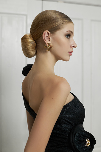 Art portrait of a young blonde woman, hair bun. Beautiful woman in black evening dress. Perfect evening makeup on face, hairstyle. fashion studio portrait of beautiful elegant woman in black