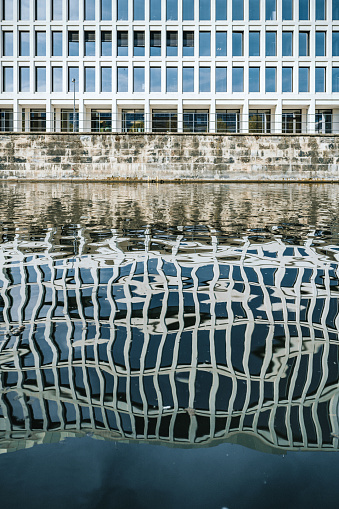 modern architecture reflecting distorted in river in central berlin