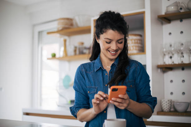 istock Beautiful woman in kitchen using phone. 1395110153