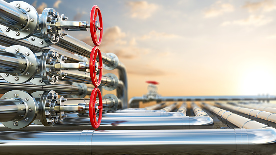 Steel pipes with red valves close up are stretching in a distance to horizon, in front of bright sun and blurred sunset background, 3d illustration