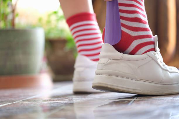istock Person puts shoes white sneakers using shoehorn 1395114779