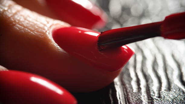 istock Master painting nails with bright red varnish to client closeup 1395114804