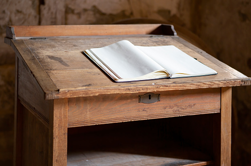 Old wooden teachers desk with open book and blank pages