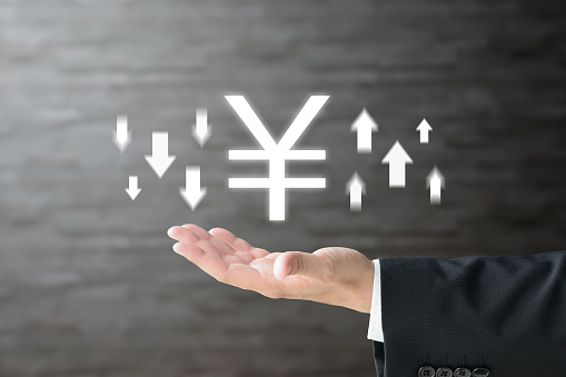 Business man's hand and Japanese yen mark with upward and downward arrows