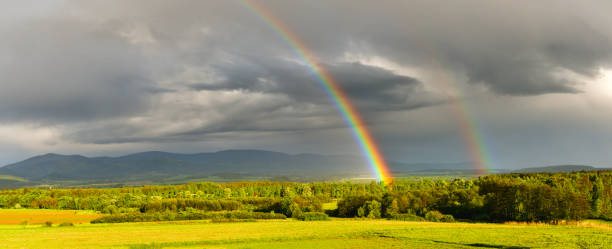 istock A storm front with numerous rainfalls passes over the mountains, the sun came out from behind the clouds, a colorful rainbow against the background of dark clouds. 1395116139