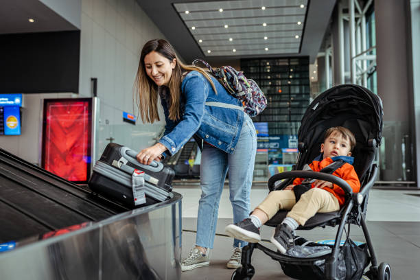 Single mother and her son waiting for luggage near conveyor belt stock photo