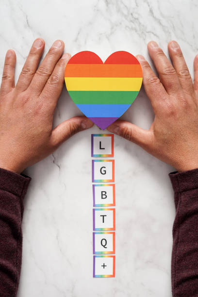 manos de un hombre maduro colocando un corazón con los colores del movimiento sobre las siglas lgbtq. concepto de tolerancia, inclusión y diversidad - lesbian gay man rainbow multi colored fotografías e imágenes de stock