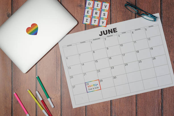 Top view of a calendar marking International Pride Day with the phrase Love is Love and the word diversity on a wooden table. Concept of tolerance, inclusion and diversity stock photo