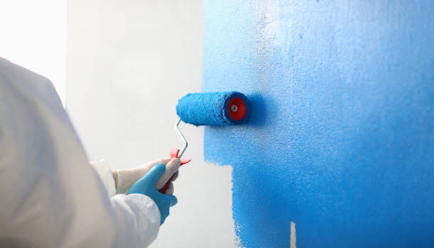 istock Painter with brush tool covered in blue colour painting wall 1395120758