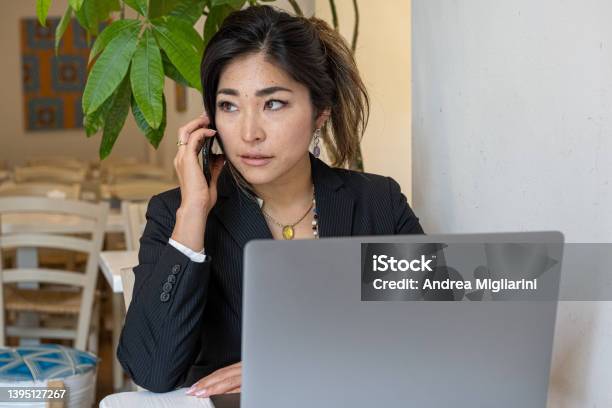 Young Japanese Female Entrepreneur Business Woman Working In A Cafeteria Using Laptop And Smartphone Stock Photo - Download Image Now