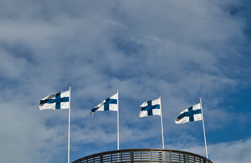 Four finnish national flags on the wind against the blue sky