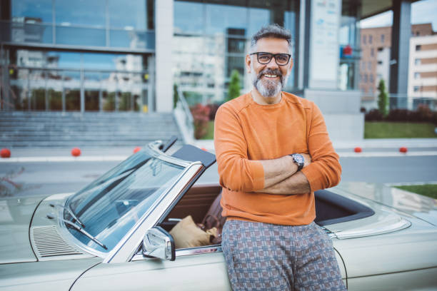 mężczyzna stojący obok swojego zabytkowego samochodu - outdoors car convertible wealth zdjęcia i obrazy z banku zdjęć