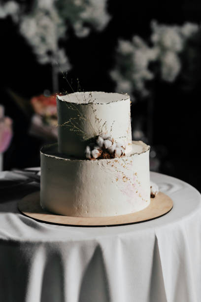 istock A wedding cake. Milk-colored cake decorated with cotton beads and gold leaf on a dark background in wedding day 1395132932