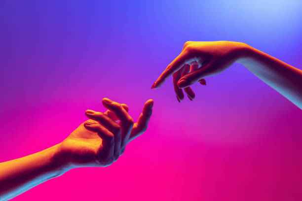 istock Two human hands trying to touch each other isolated on gradient blue-pink background in neon light. Concept of human relation, togetherness, symbolism, culture and history 1395134852