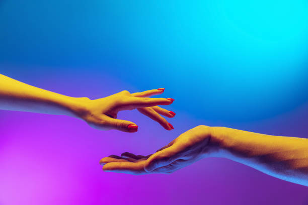 istock Two authentic hands trying to touch each other isolated on gradient blue purple background in neon light. Concept of relationship, community, care, support, symbolism 1395134920