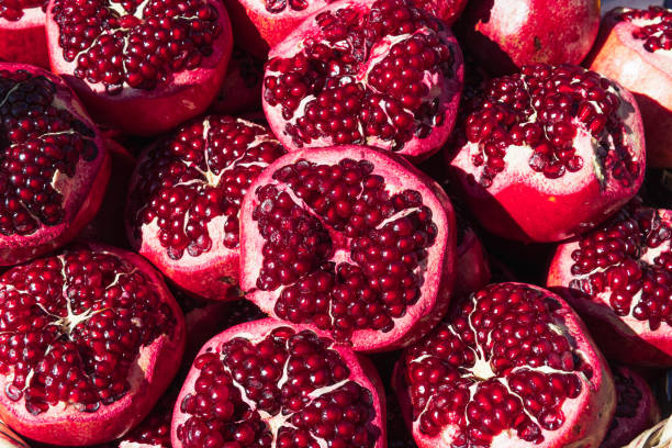 a lot of ripe red pomegranates with a cut off top, close-up background a lot of ripe red pomegranates with a cut off top, close-up background, space for an inscription. High quality photo pomegranate stock pictures, royalty-free photos & images