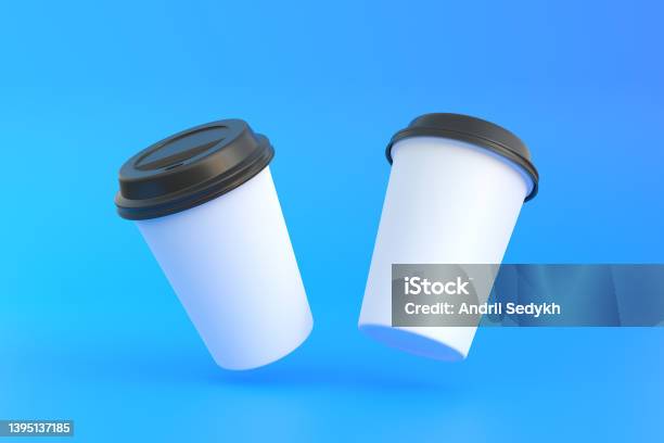 Two Disposable Paper Coffee Cup With Black Lid In The Air Over Blue Background Stock Photo - Download Image Now