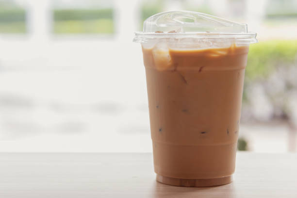 Thai tea, iced milk tea with milk in a plastic cup on a wooden table in a coffee shop.