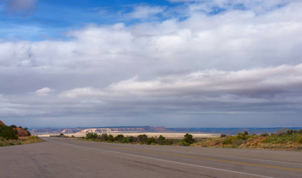 A highway goes to the horizon. The road passing through the prairie against the backdrop of a mountain landscape. stratus clouds stock pictures, royalty-free photos & images