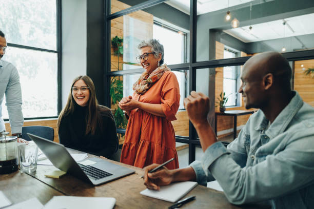 diverse businesspeople smiling cheerfully during an office meeting - leidinggevende stockfoto's en -beelden