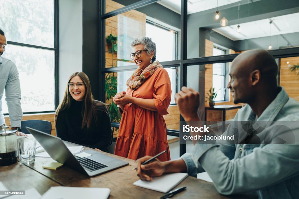 Diverse businesspeople smiling cheerfully during an office meeting Diverse businesspeople smiling cheerfully during a meeting in a modern office. Group of successful businesspeople working as a team in a multicultural workplace. Office Stock Photo