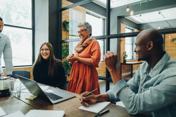 Diverse businesspeople smiling cheerfully during an office meeting Diverse businesspeople smiling cheerfully during a meeting in a modern office. Group of successful businesspeople working as a team in a multicultural workplace. employee stock pictures, royalty-free photos & images