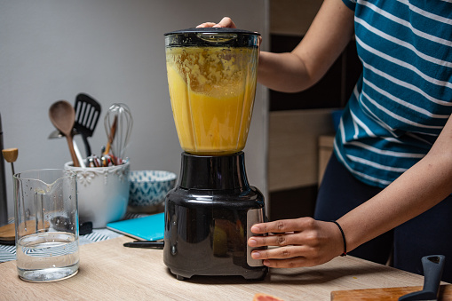 Young woman preparing fruits for natural juice