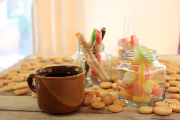 Closeup of a hand holding a chocolate chip cookie next to a cup of coffee