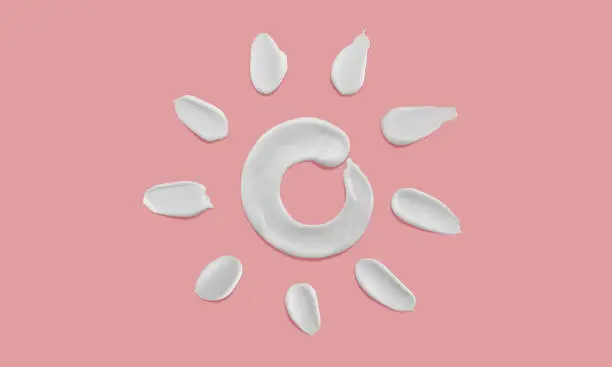 Photo of Sunscreen cream sun shape smears on pink background, moisturiser brush stroke sun drawing