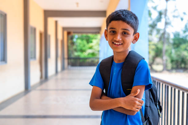 istock happy smiling kid with backpack confidently standing by with crossed arms by looking camera at school corridor - concept of back to school, education and learning 1395154411
