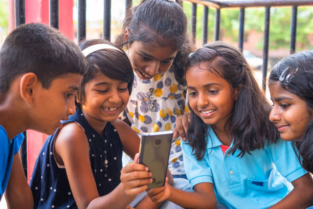 istock Kids at school busy using mobile phone while sitting at corridor during break - concept of technology, smartphone addiction and using social media 1395154595