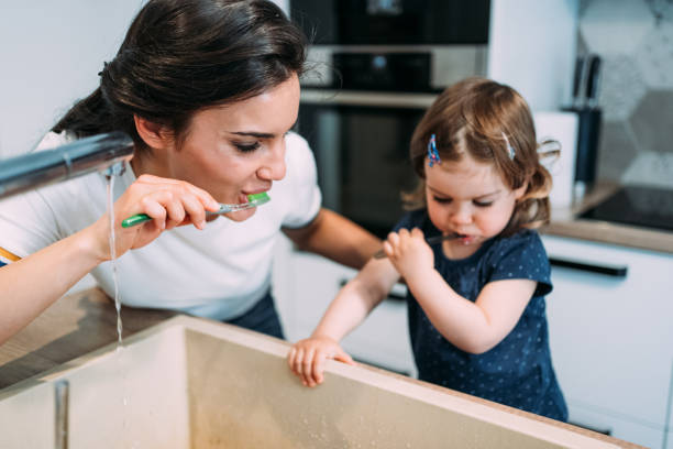 istock Mother and daughter brushing teeth together. 1395154813